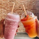 people holding cups of smoothie