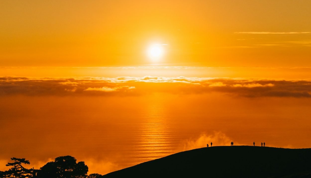 people on top of hill under white clouds golden hour photography