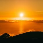 people on top of hill under white clouds golden hour photography