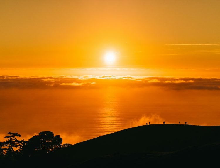 people on top of hill under white clouds golden hour photography