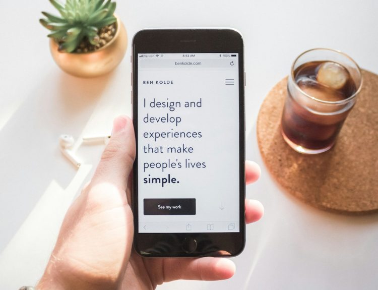 person holding space gray iPhone 6 displaying i design and develop experiences that make people's lives simple text