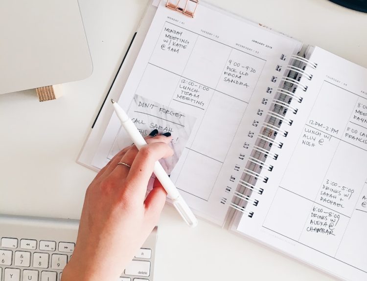 person holding notepad and pen flat lay photography