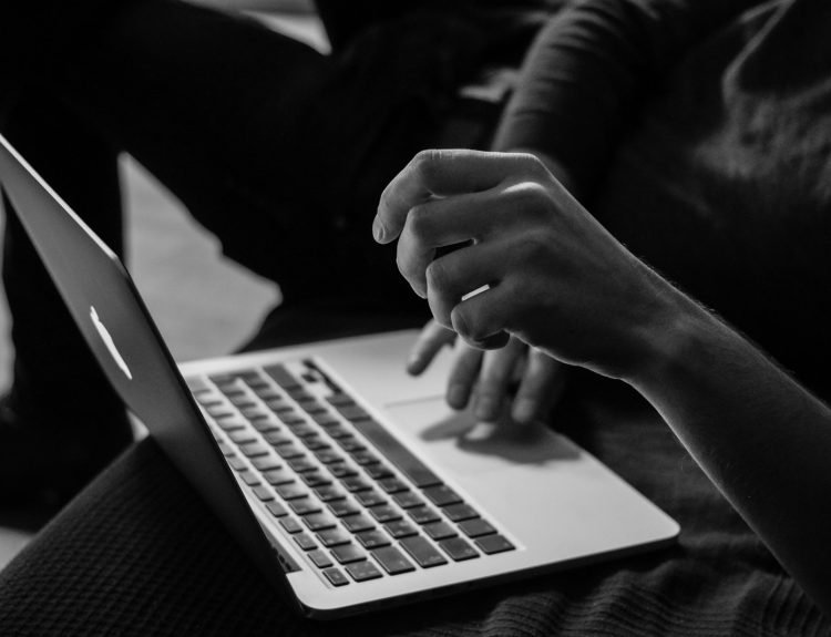 grayscale photo of person using MacBook