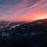 Capture of the vibrant Los Angeles skyline under a dramatic sunset sky.