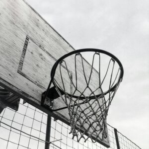 Monochrome shot of a basketball hoop against the sky, capturing the essence of outdoor sports.