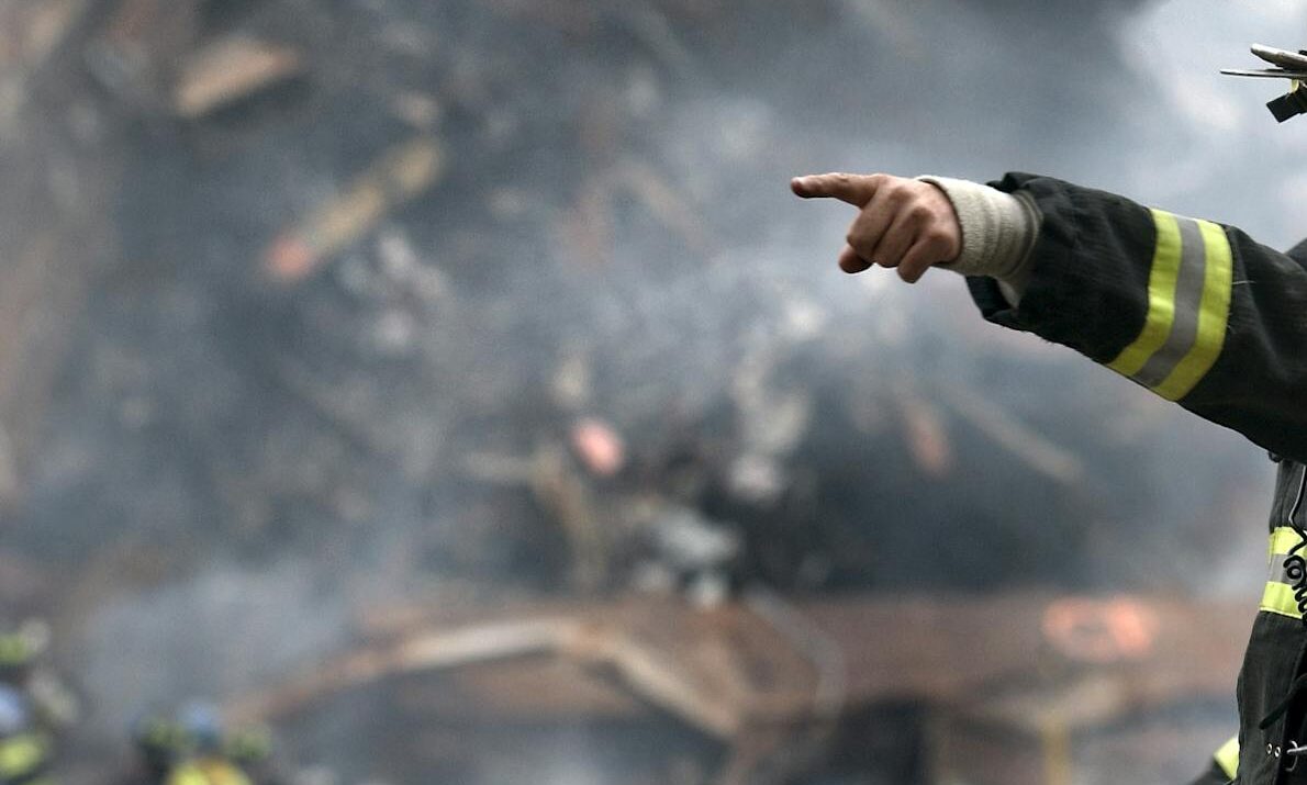 A firefighter in action at a disaster scene, directing rescue operations amidst smoke and debris.