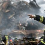 A firefighter in action at a disaster scene, directing rescue operations amidst smoke and debris.