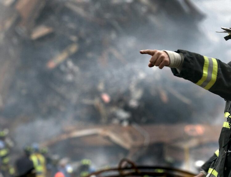 A firefighter in action at a disaster scene, directing rescue operations amidst smoke and debris.