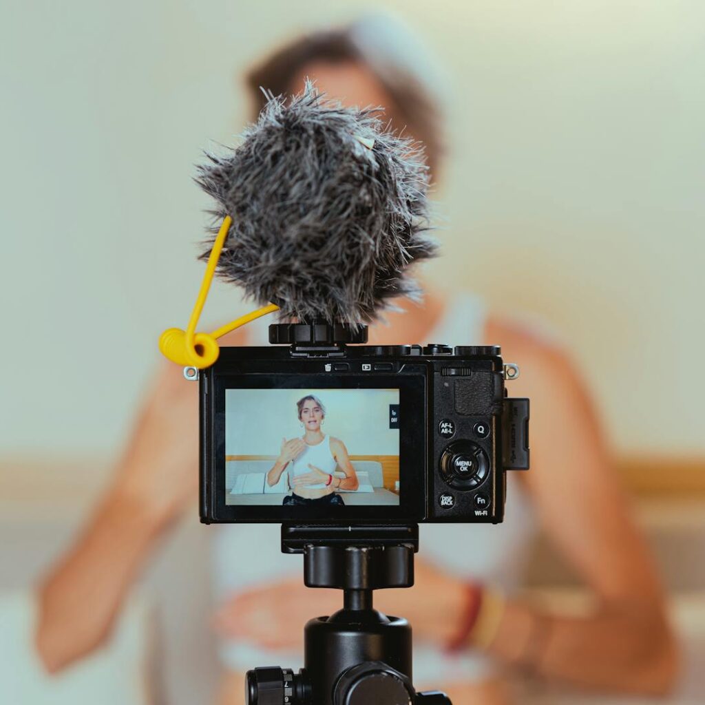 Elderly woman engages in vlogging using camera and microphone, embracing modern technology.